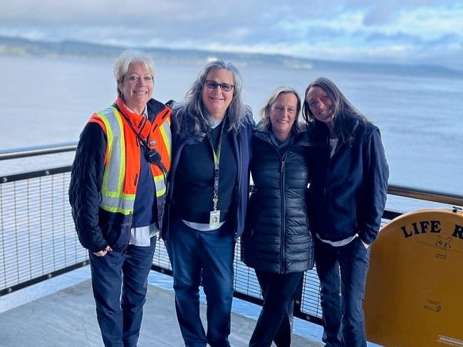 Four people posing for a photo on an outdoor patio at a ferry terminal